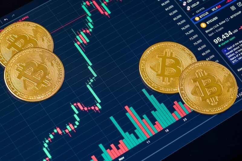 Golden Bitcoin cryptocurrency symbol standing in front of Bitcoin's rise and fall chart